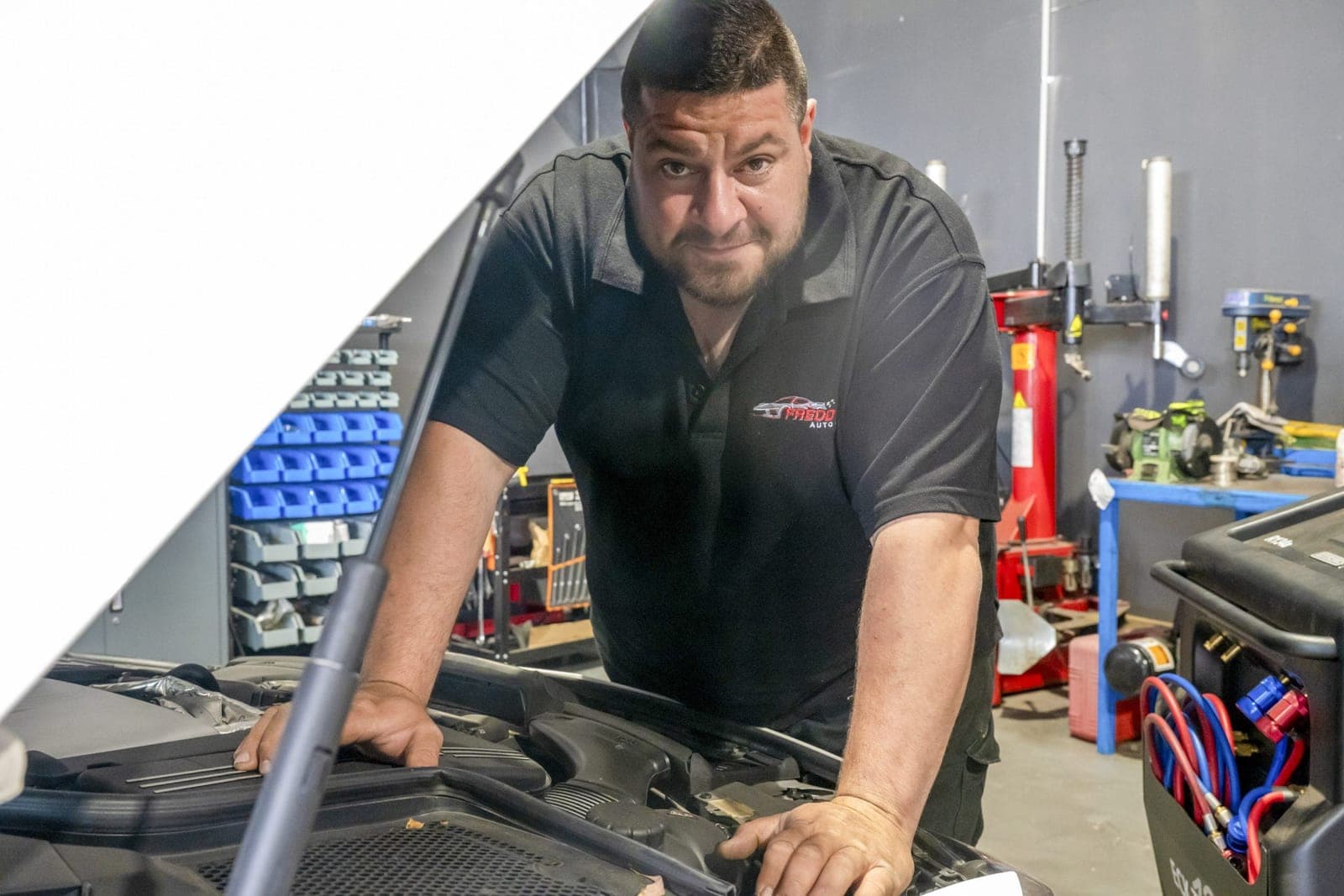 Mechanic working in the engine bay of a vehicle during a service